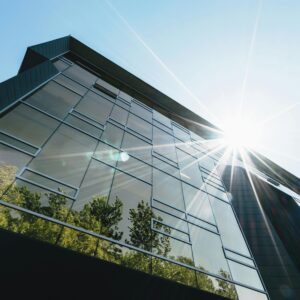 Low angle view of a modern skyscraper with reflections and sun flare, emphasizing contemporary architecture.